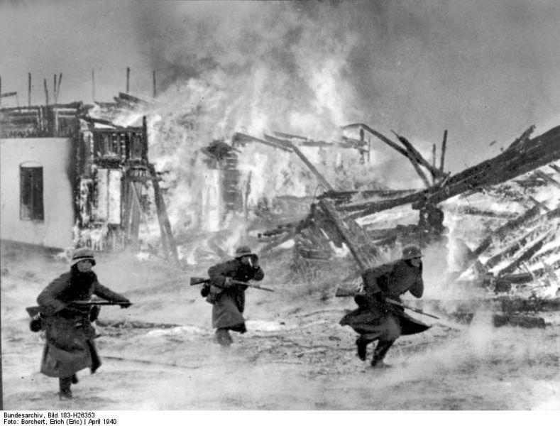 German soldiers advance through a burning Norwegian Village, April 1940